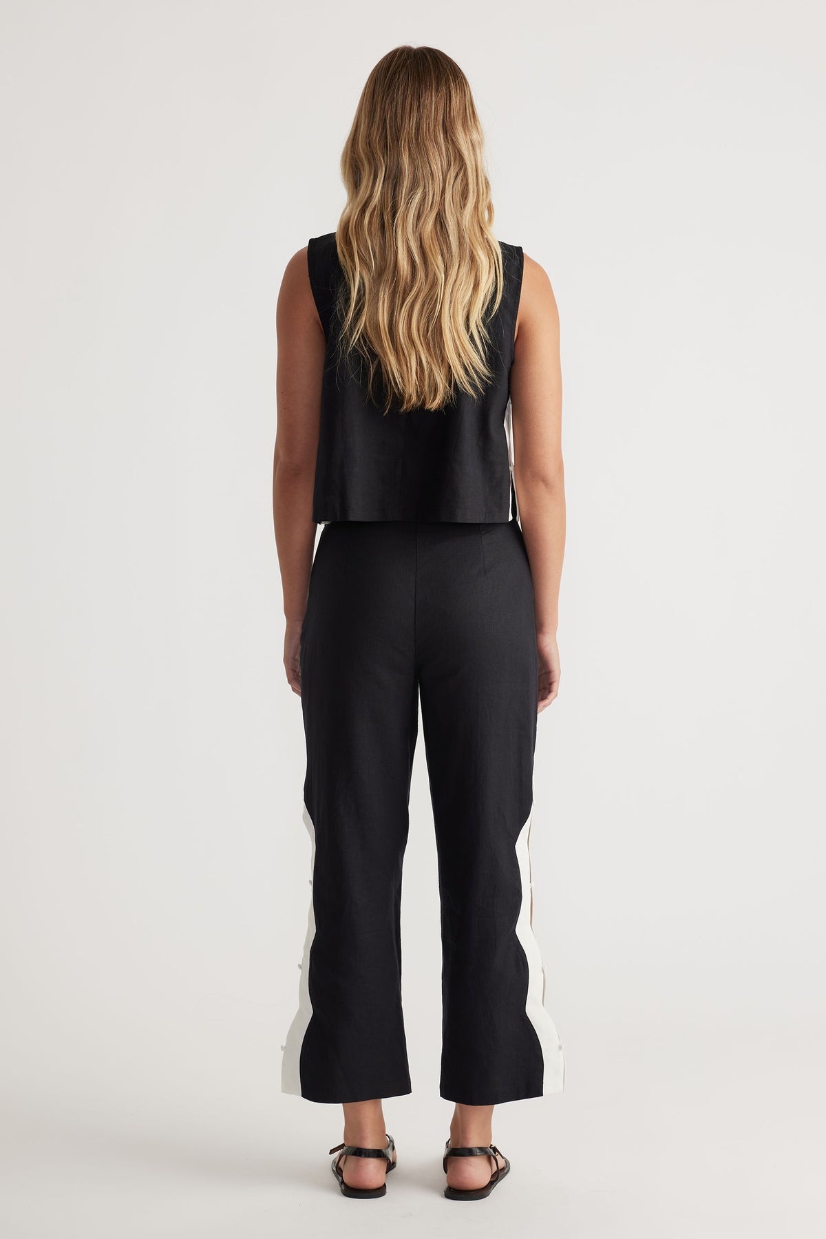 Back view portrait of model wearing Tess Scallop Pant with contrast solid edge side splits and button closures, gallery 3.
