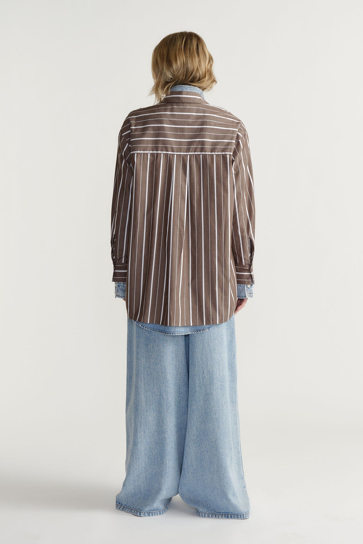 Back view of D-Luxe Poplin Stripe Shirt in gallery position 3, featuring a brown and white stripe design with denim pants