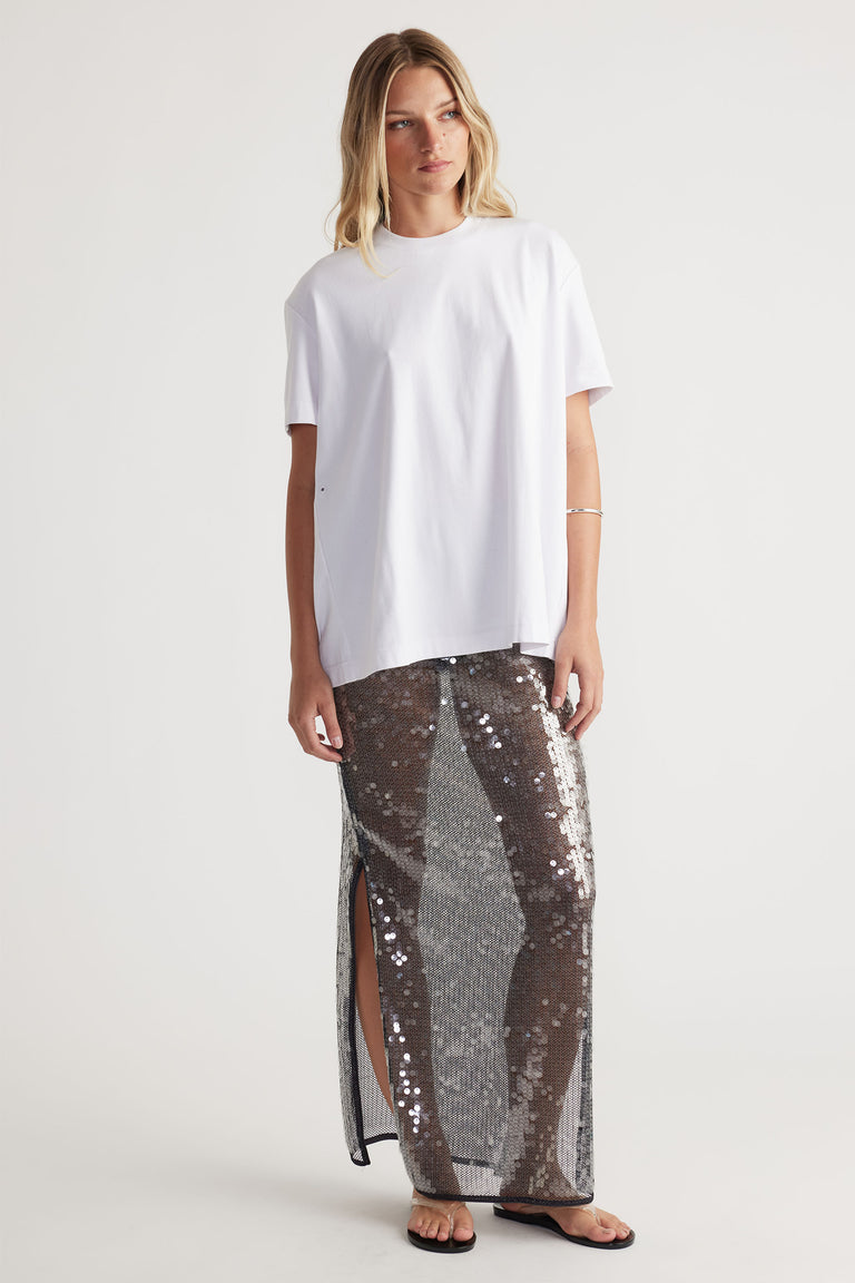 Woman wearing a white oversized tee and a semi sheer Savannah Sequin Skirt with side splits in portrait gallery position 1