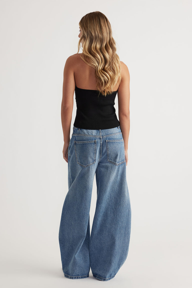 Back view of woman wearing a black halter tank paired with light blue wide-leg denim jeans for a relaxed look