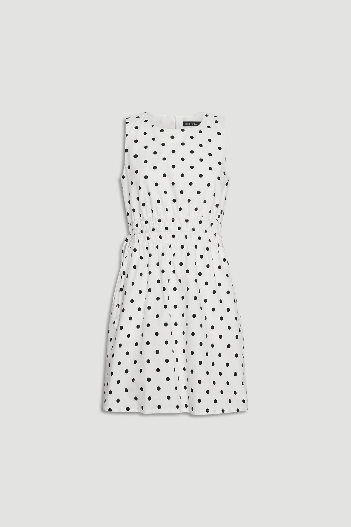 Cali Spot Mini Dress in portrait view showcasing sleeveless design with shirred waist and black polka dots on white fabric.