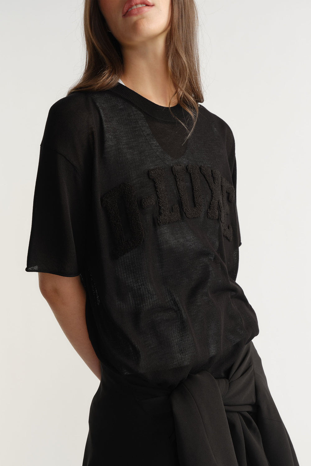 Portrait view of semi-sheer black D-Luxe Fine Knit Tee with bouclé logo across chest in gallery position 2.