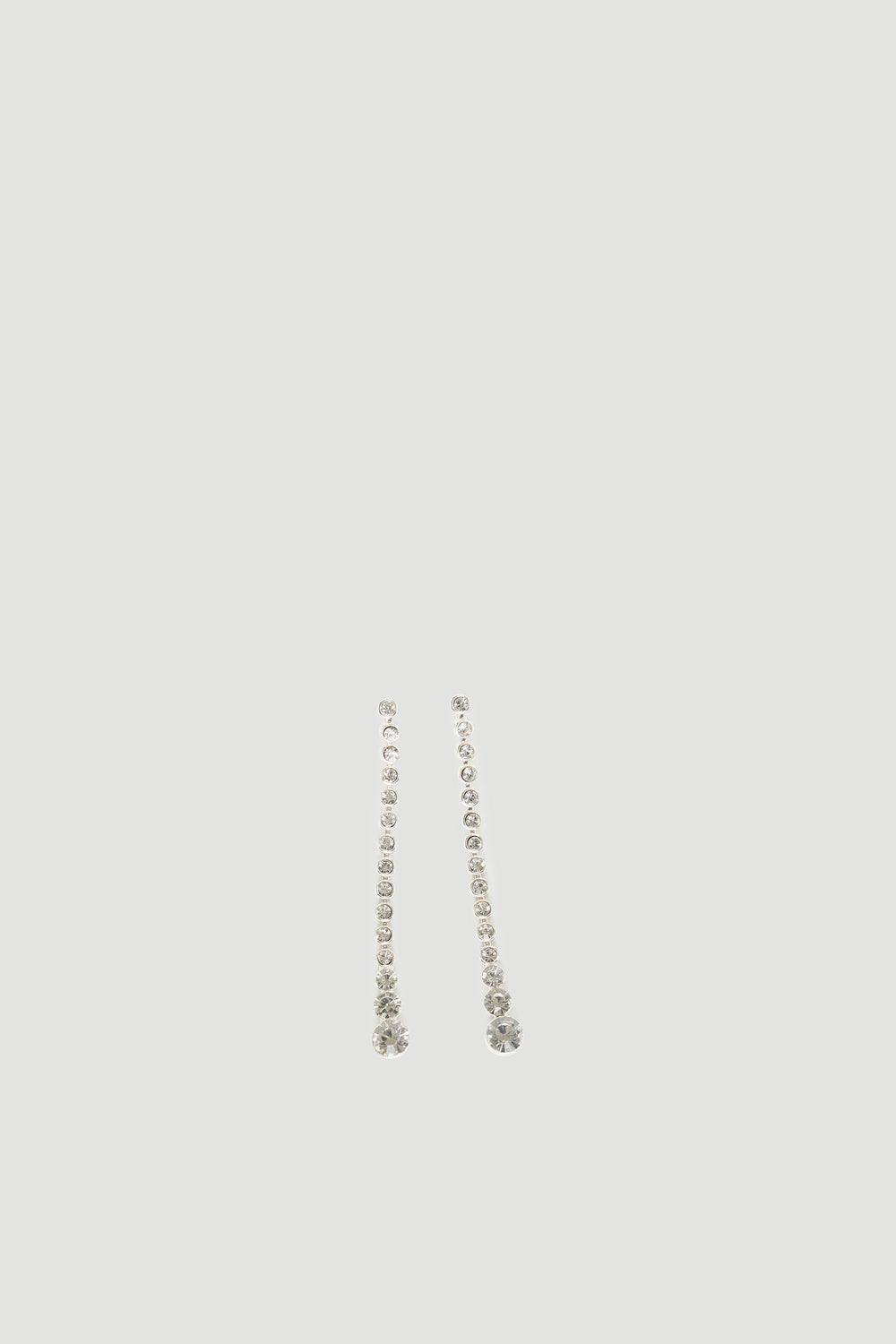 Delicate silver drop earrings featuring a vertical line of sparkling diamante stones with a larger gem at the base
