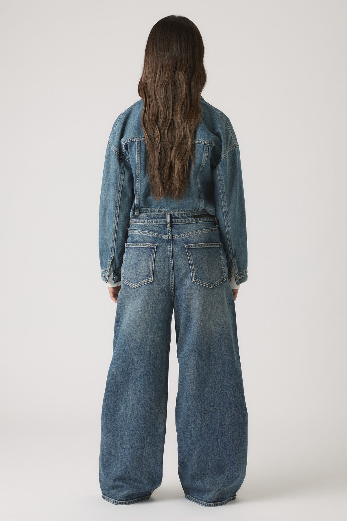 Girls Dad Baggy Jean in soft mid-blue denim with a relaxed, wide-leg fit styled with a cropped jacket by DECJUBA Australian brand