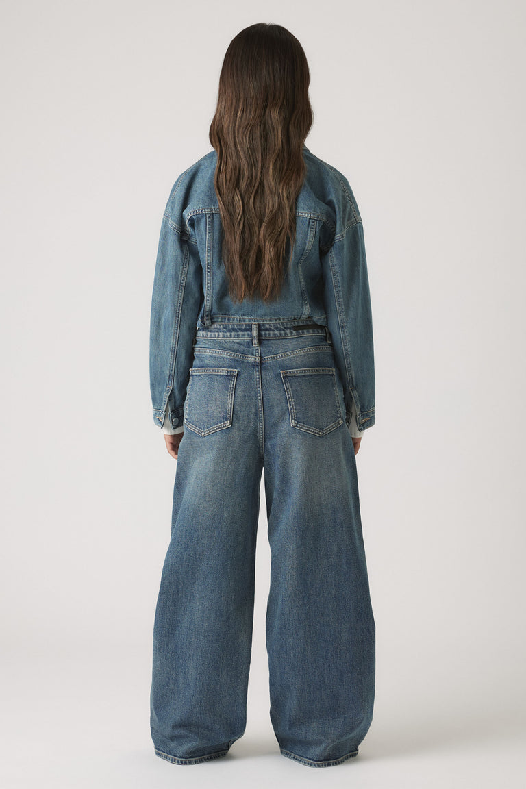 Girls Dad Baggy Jean in soft mid-blue denim with a relaxed, wide-leg fit styled with a cropped jacket by DECJUBA Australian brand