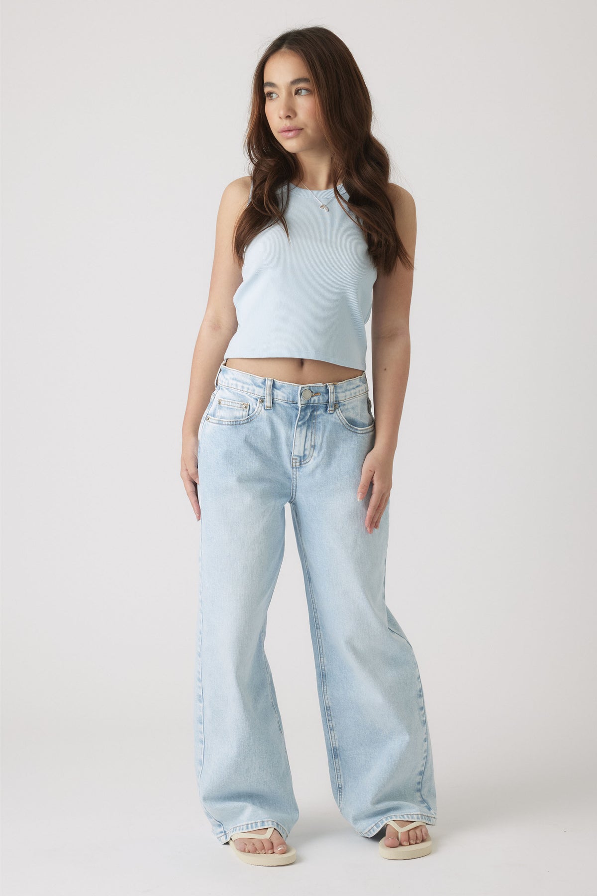 Girl wearing a pale blue sleeveless tank paired with relaxed light wash wide-leg jeans and sandals for casual style