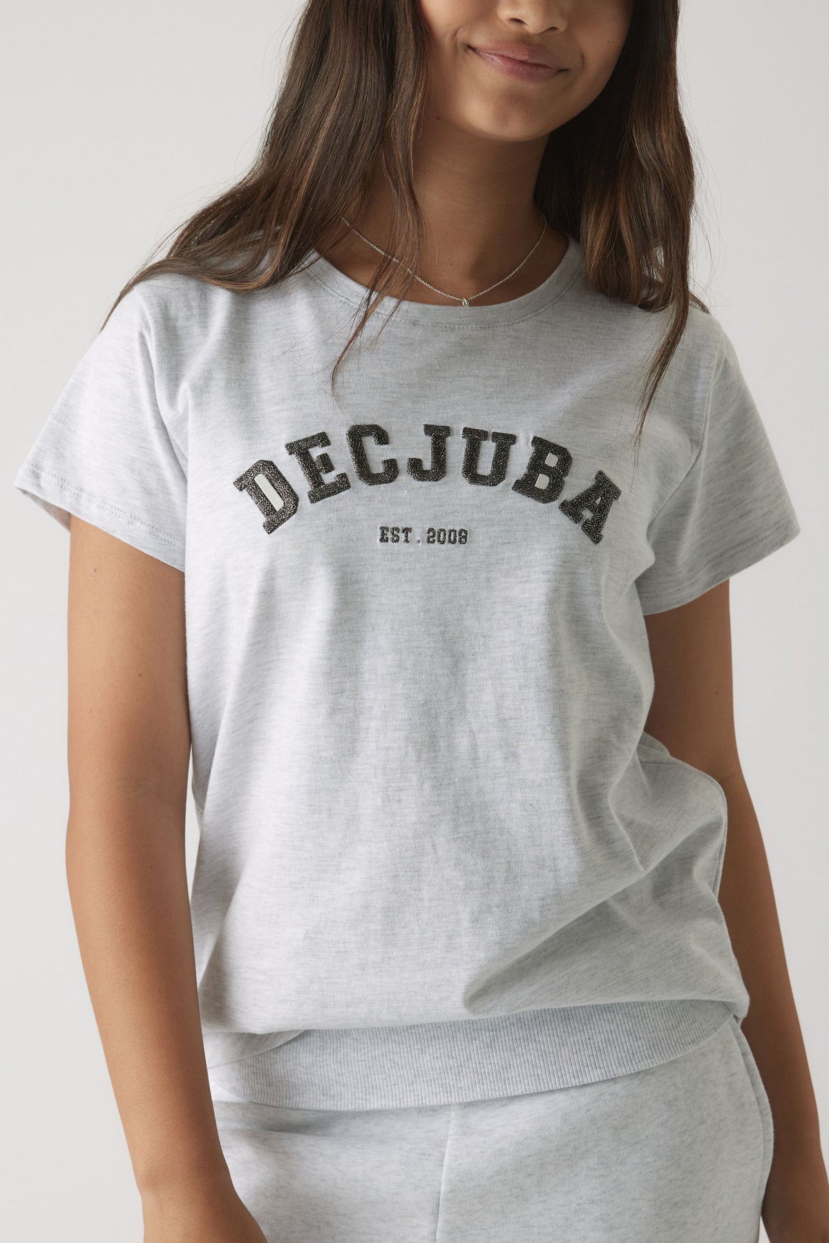 Girl wearing a soft light grey tee with black vintage-style logo print for casual everyday comfort and effortless style
