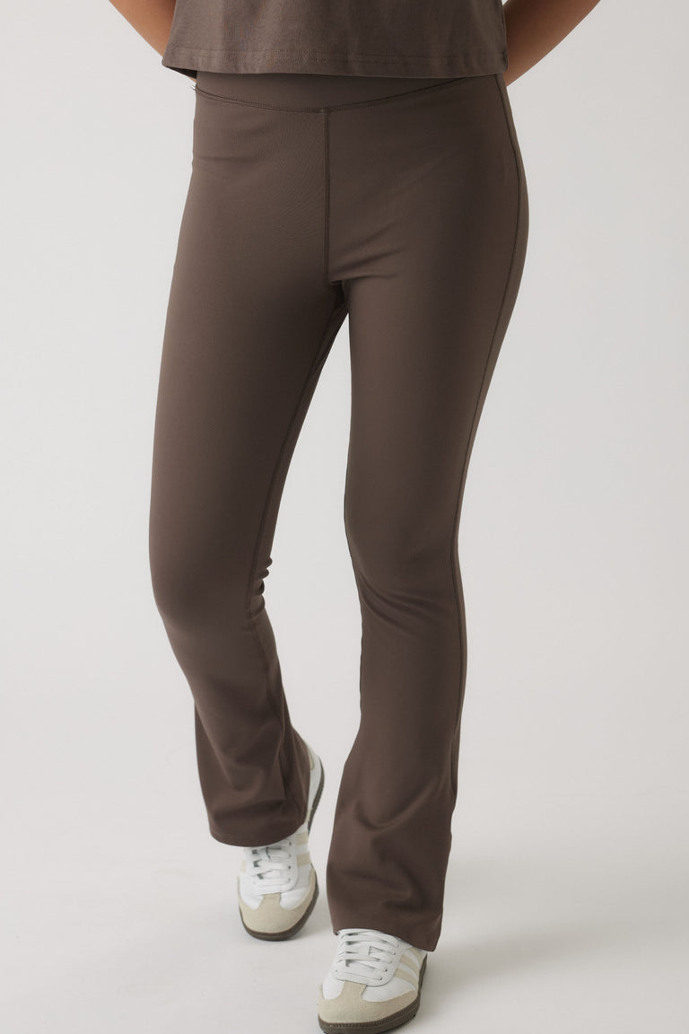 Close-up of a girl wearing mocha-colored fitted yoga pants with a slight flare paired with white sneakers