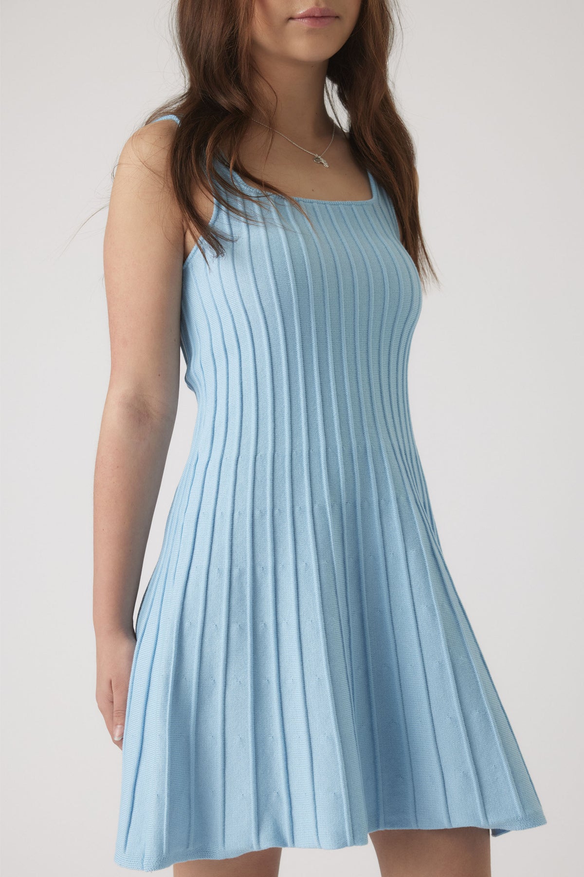 Girl wearing a sky blue ribbed knit dress with thin straps and a flared skirt, styled simply for everyday wear.