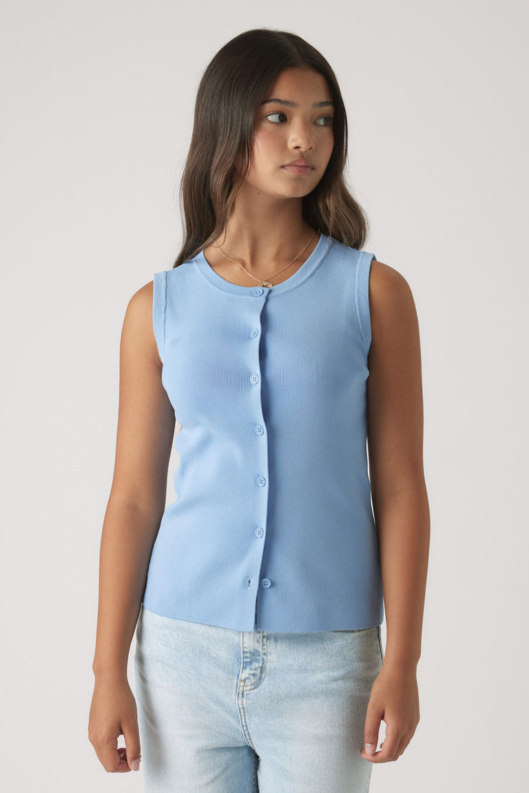 Girl wearing a soft dusty blue sleeveless knit vest with button front paired with light wash denim jeans