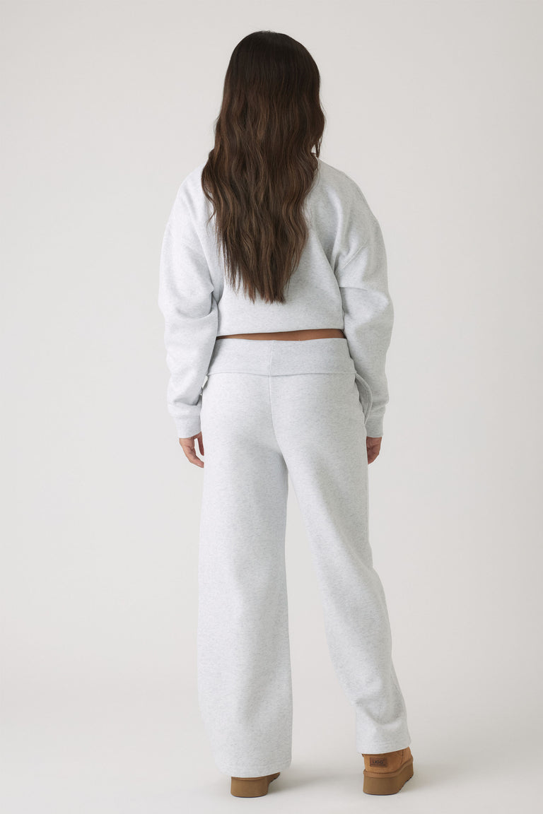 Back view of girl wearing light grey rolled waist track pants paired with matching cropped sweatshirt and boots