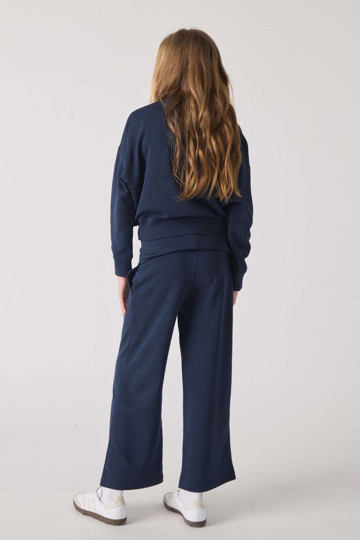 Girl wearing relaxed navy fleece pants and matching bomber jacket paired with white sneakers for casual comfort.
