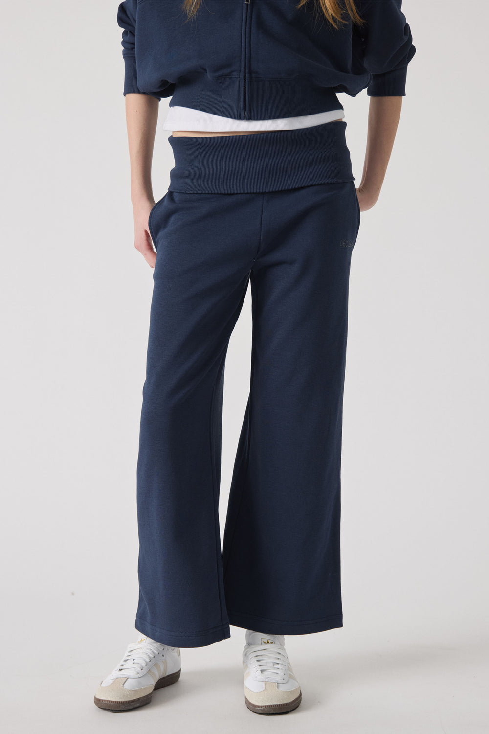 Girl wearing navy wide-leg rolled waist pants paired with white sneakers for a comfortable, sporty look