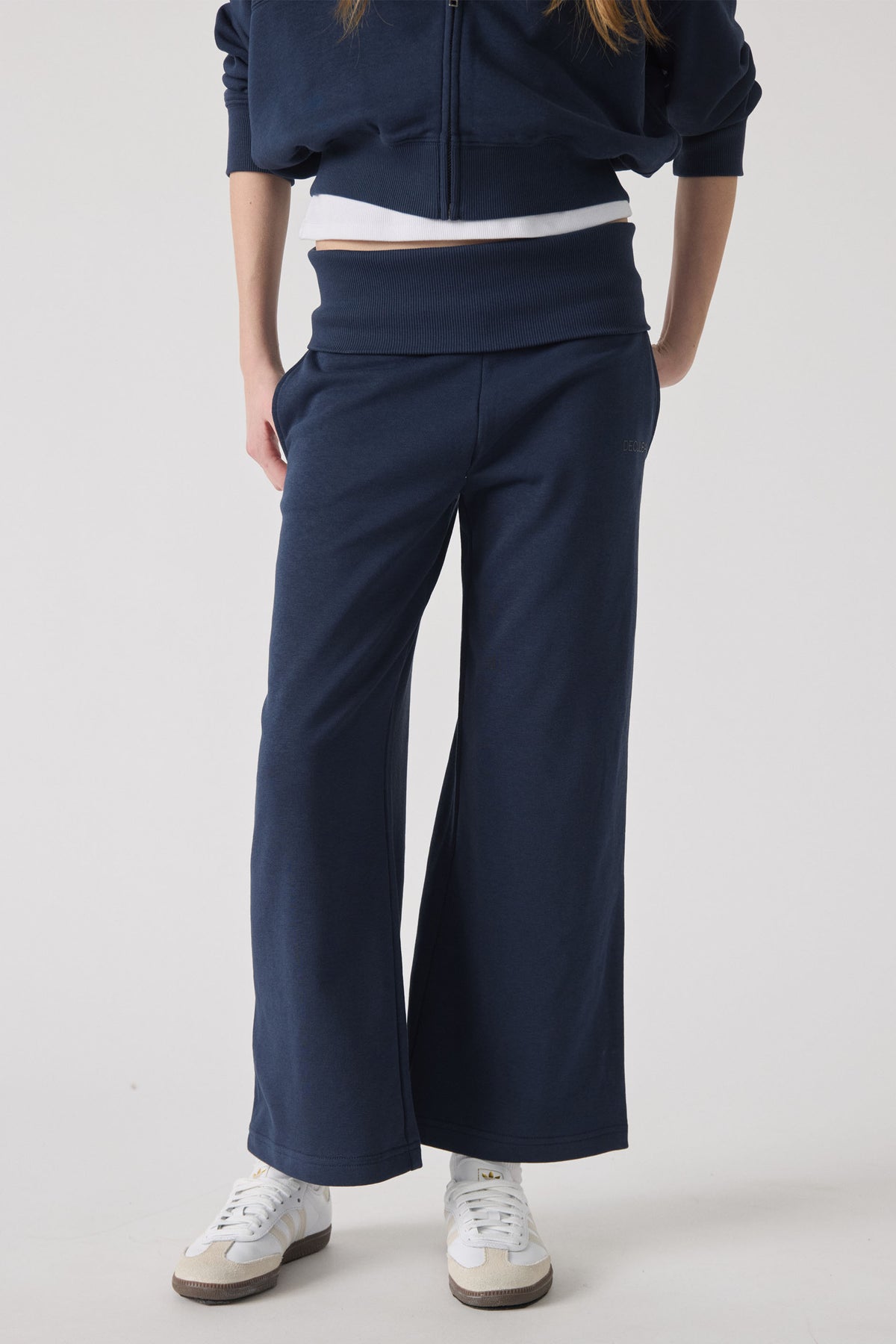 Girl wearing navy wide-leg rolled waist pants paired with white sneakers for a comfortable, sporty look