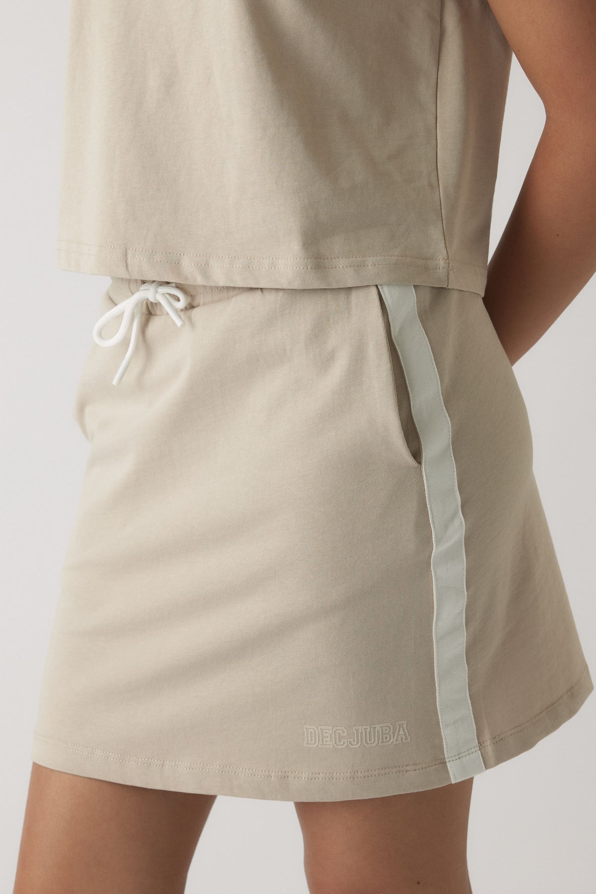 Girl wearing a beige casual skirt with side stripe and drawstring waist for an easy everyday look