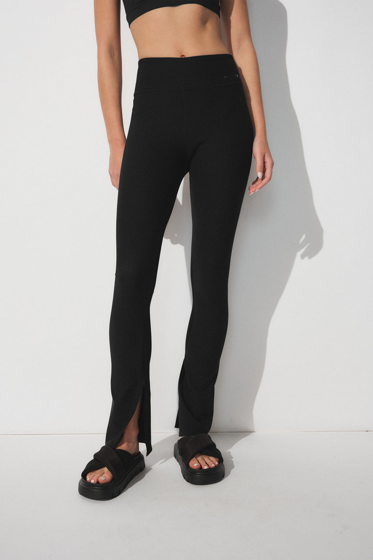 Black ribbed leggings with a split hem detail, styled with casual black platform sandals for an effortless look.