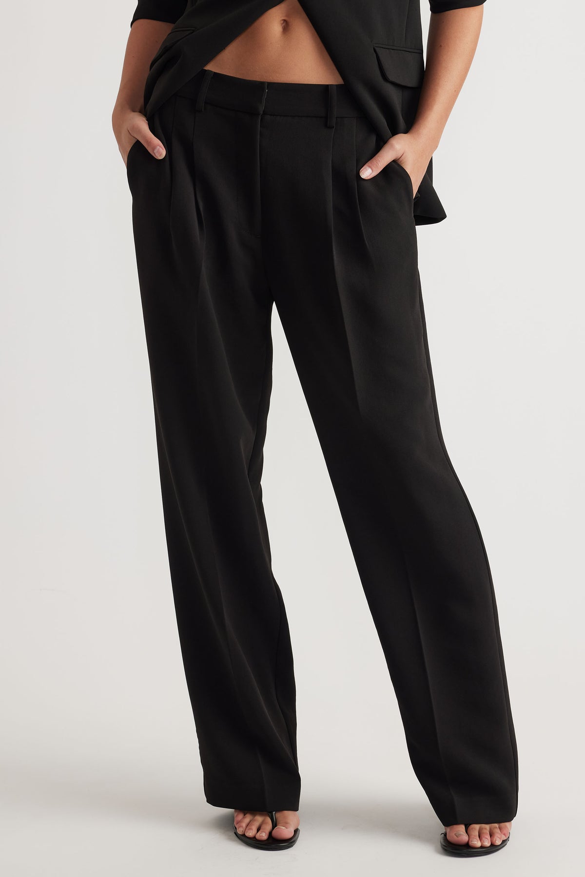 Front view of black tailored pants with a relaxed fit styled with a black blazer and open-toe heels