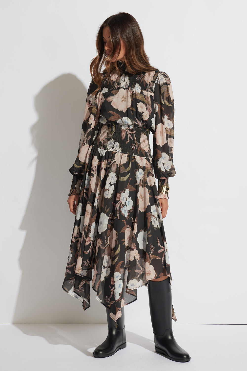 Woman wearing a floral midi dress with shirred detailing and puff sleeves paired with knee-high black boots