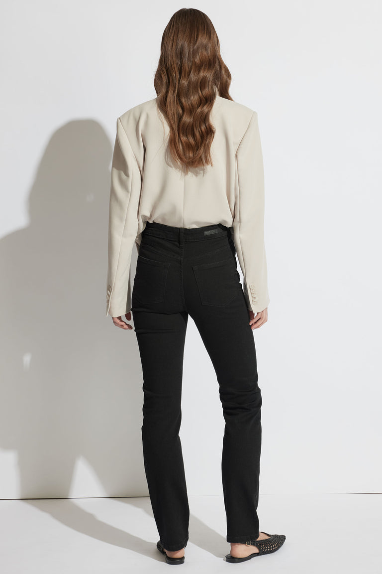 Back view portrait of woman wearing black Billie Straight Leg Jean paired with beige top, gallery position 3 in soft denim