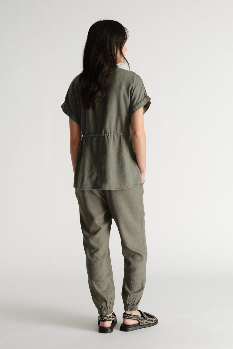 Woman seen from behind wearing relaxed-fit thyme green linen blend joggers paired with a matching short-sleeve top