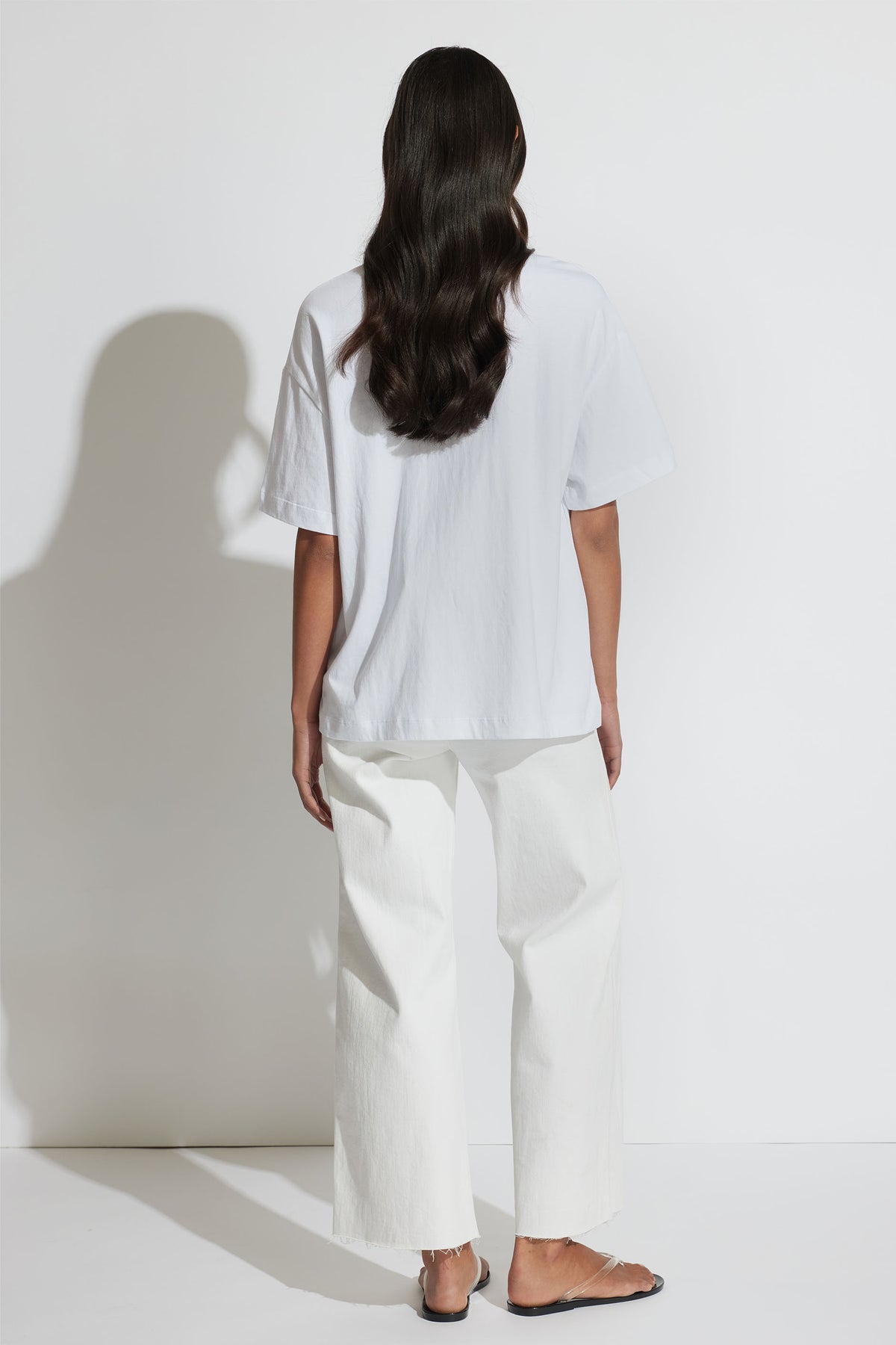 Back view of model wearing oversized Coastal Beaded Tee in white with relaxed fit and heavy cotton fabric, gallery position 3 portrait
