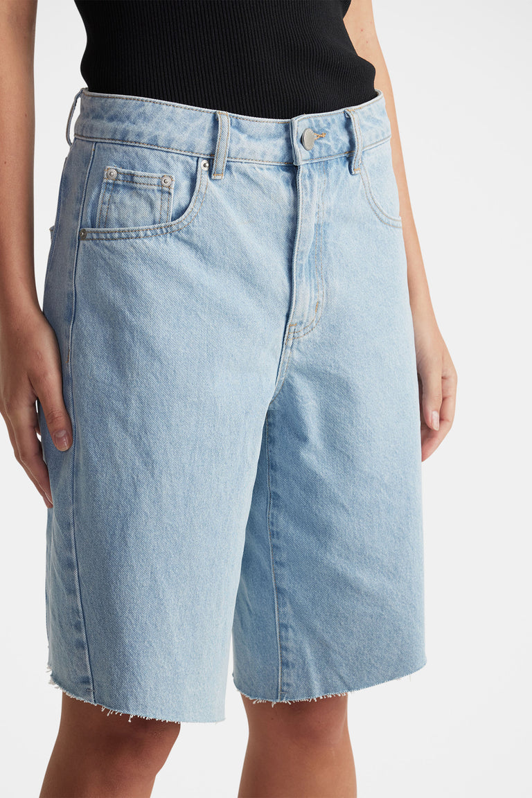 Light wash denim shorts with raw hem, mid-rise waist, and classic five-pocket design for casual, everyday style