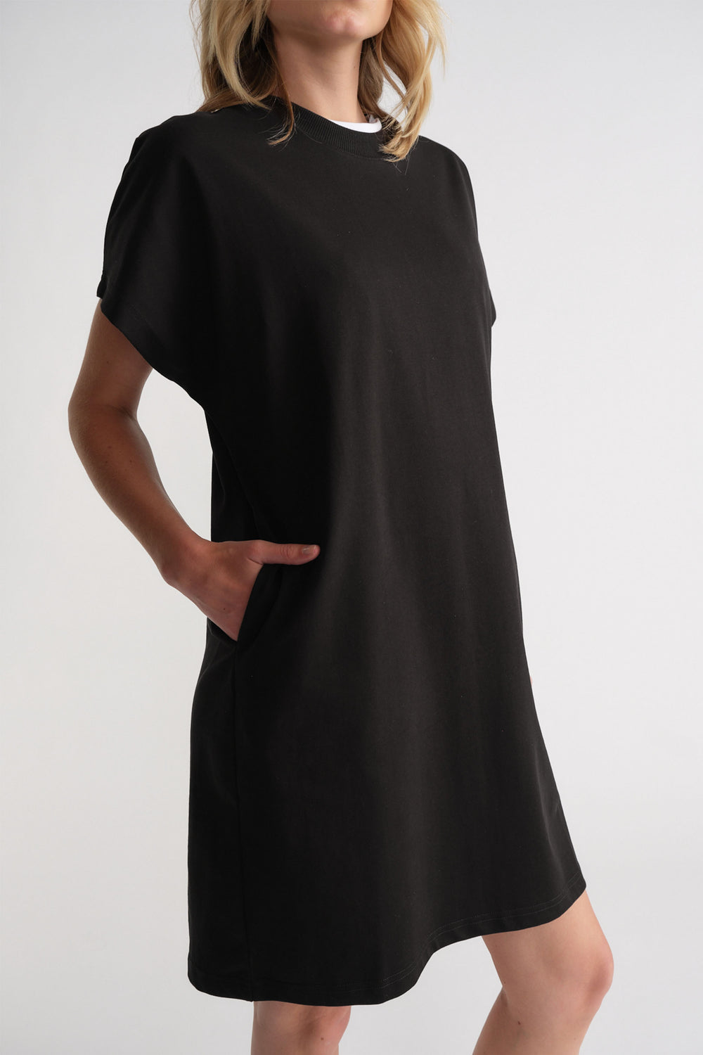 Woman wearing a relaxed black short sleeve tee dress with side pockets for an effortless casual look