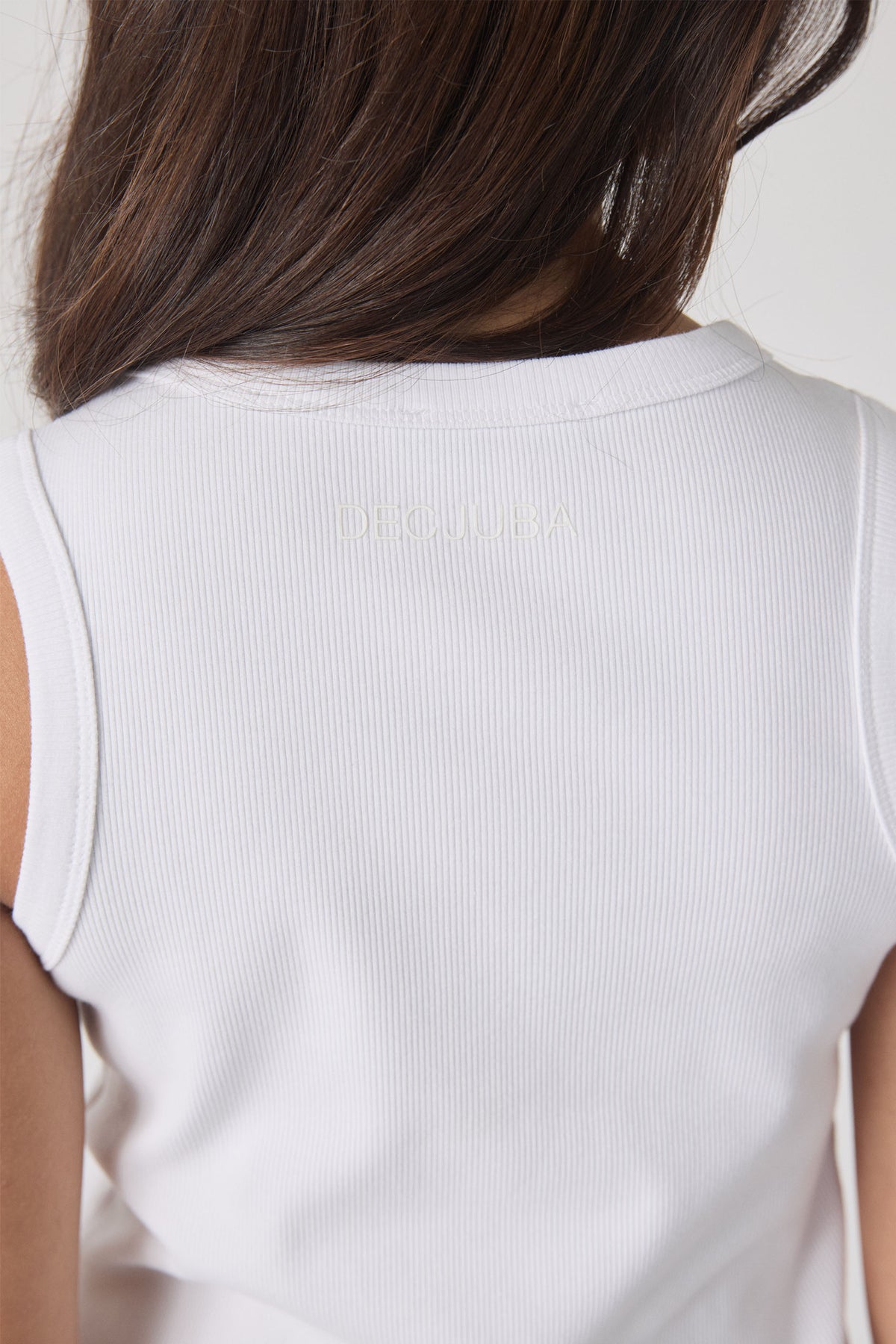 Back view of a soft white ribbed tank top with subtle logo detail on the upper back for a clean, classic look.