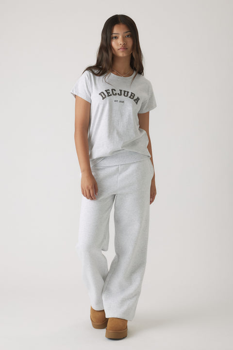 Girl wearing a light grey casual tee with logo text paired with matching relaxed sweatpants and tan slip-on boots