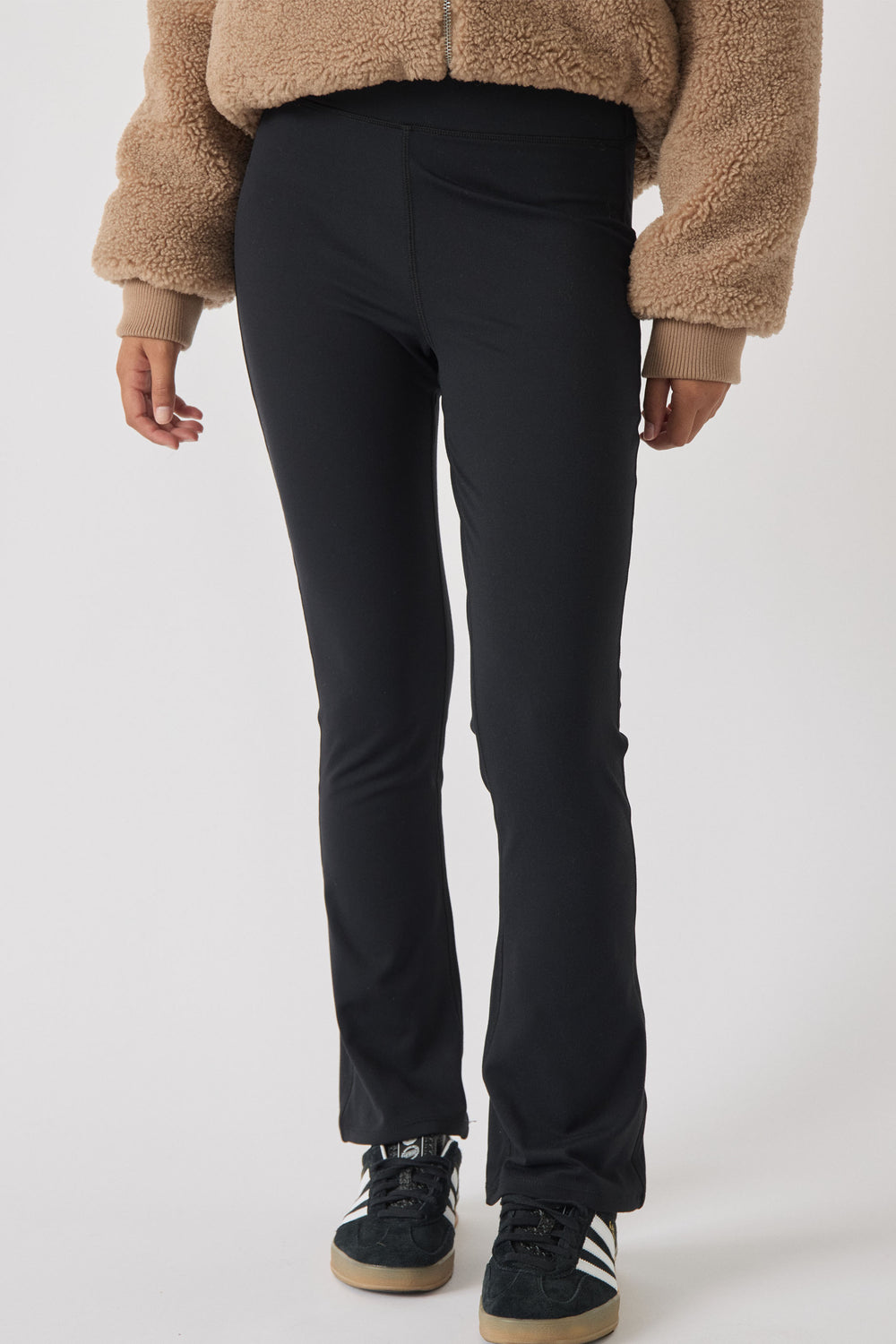 Slim fit black yoga pants on a girl paired with a cozy teddy fleece jacket and casual sneakers