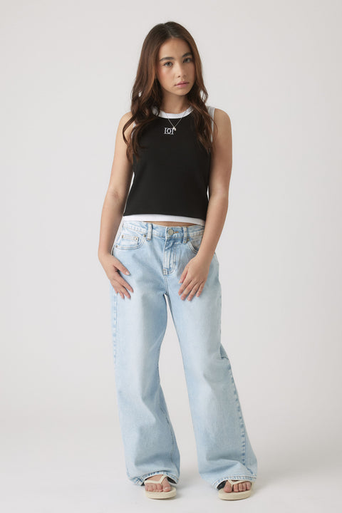 Teen girl wearing a black and white sleeveless tank paired with light-wash wide-leg jeans and sandals for casual style