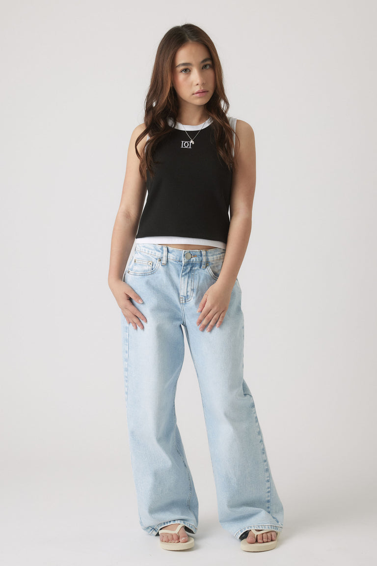 Teen girl wearing a black and white sleeveless tank paired with light-wash wide-leg jeans and sandals for casual style