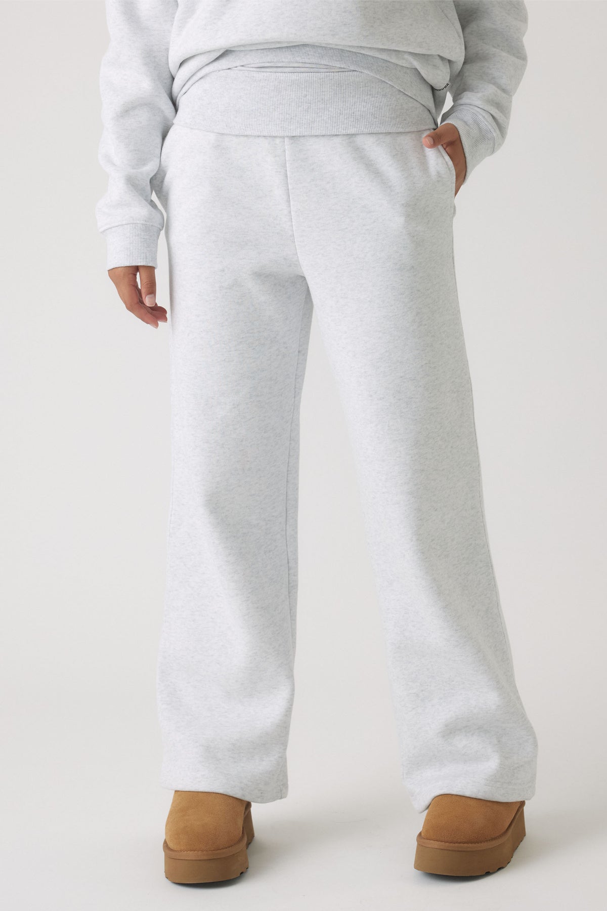 Light grey rolled waist track pants with relaxed legs styled with tan slip-on boots for a casual look