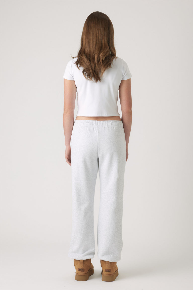 Girl wearing light grey elastic cuff track pants paired with a fitted white crop top and tan boots for casual style.
