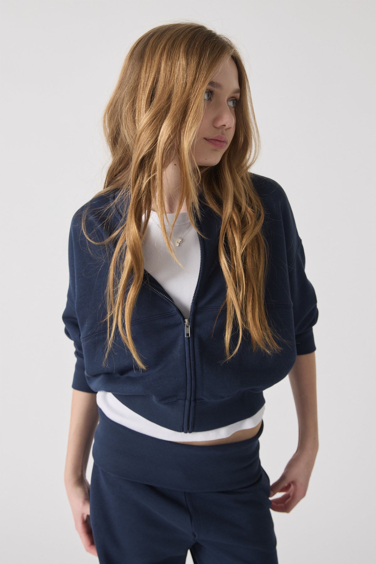 Teen girl wearing a navy fleece bomber with a front zipper over a white top, styled for casual comfort and everyday wear.