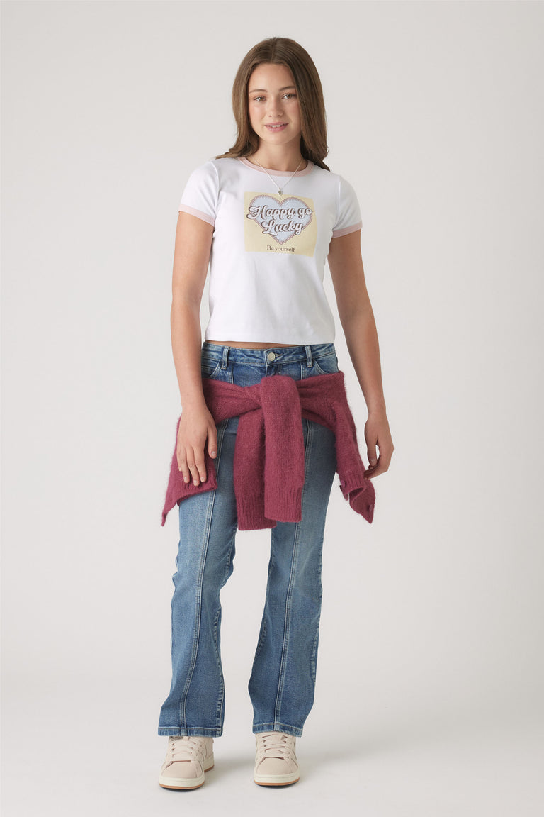 Girls Cropped Ringer Tee in white with graphic heart print, styled with blue denim jeans and cozy berry knit tied at waist by DECJUBA