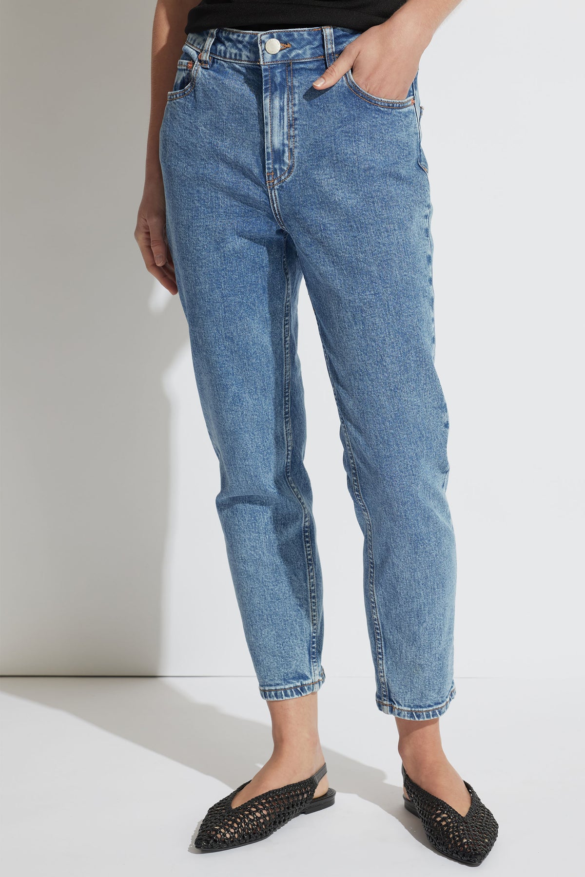 Mid-rise light blue denim jeans in a relaxed fit with rolled hems paired with black woven slip-on flats.