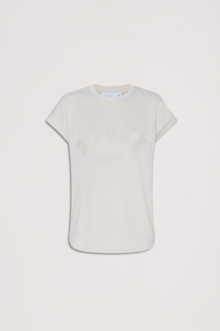 Soft shell-colored tee with subtle tonal collegiate lettering and relaxed short sleeves for casual everyday style.