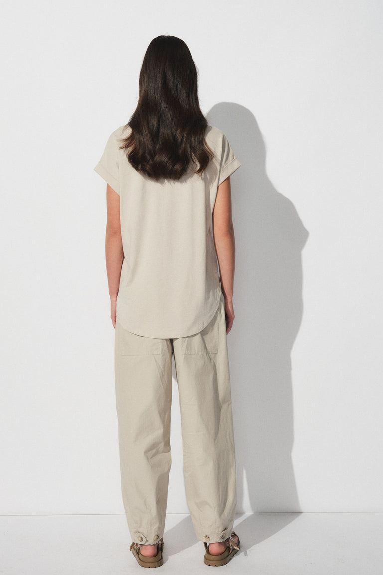 Woman wearing a relaxed beige tee and matching loose pants, standing against a plain white background in casual style.