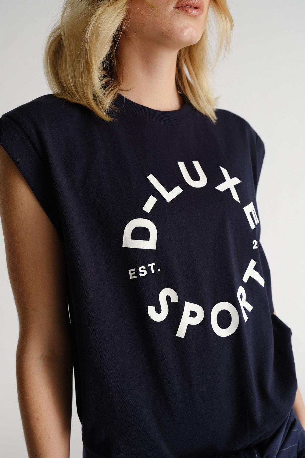 Woman wearing a navy sleeveless tank with bold white circular text for a relaxed sporty look