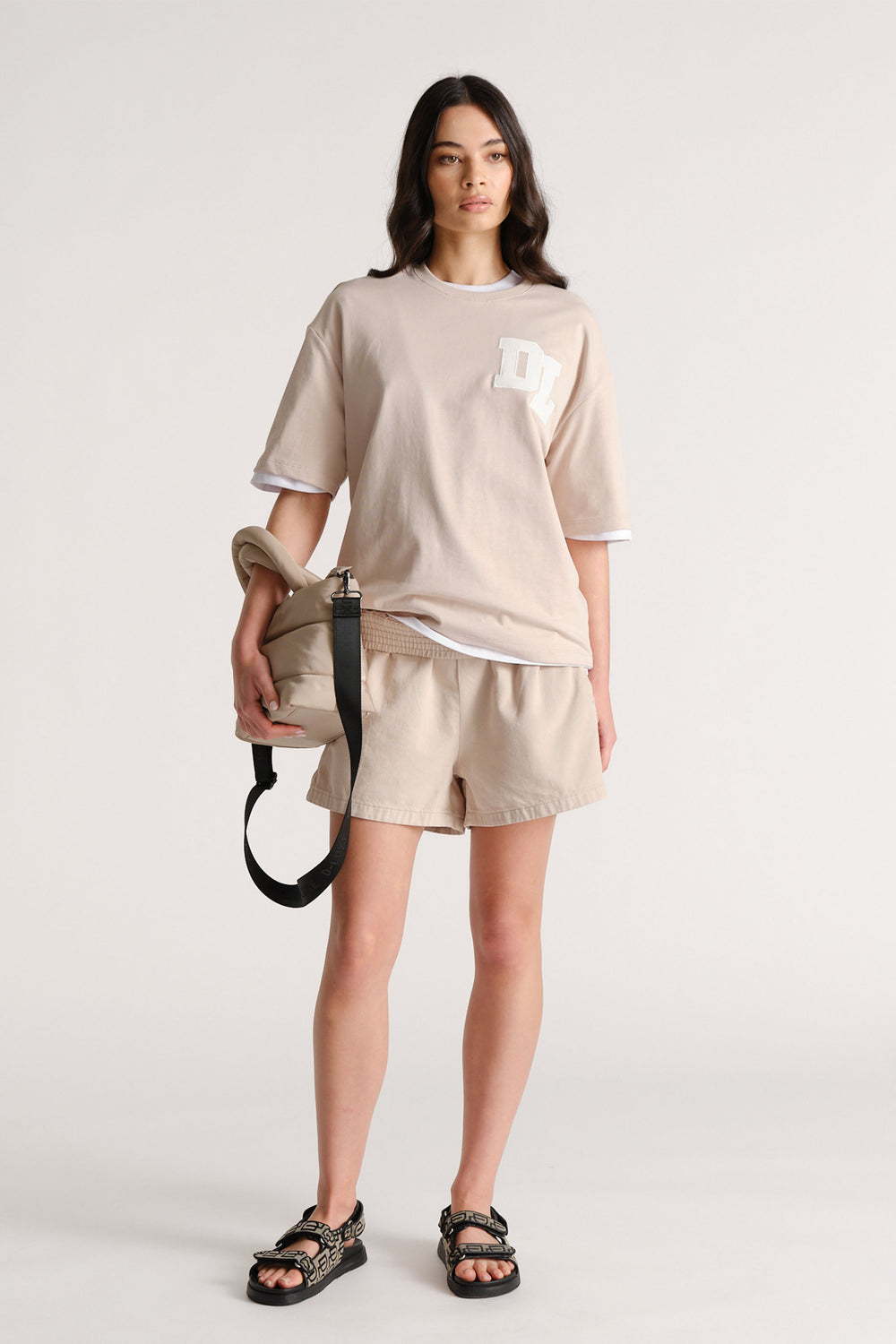 Woman wearing beige denim pull on shorts with a relaxed T shirt and sandals