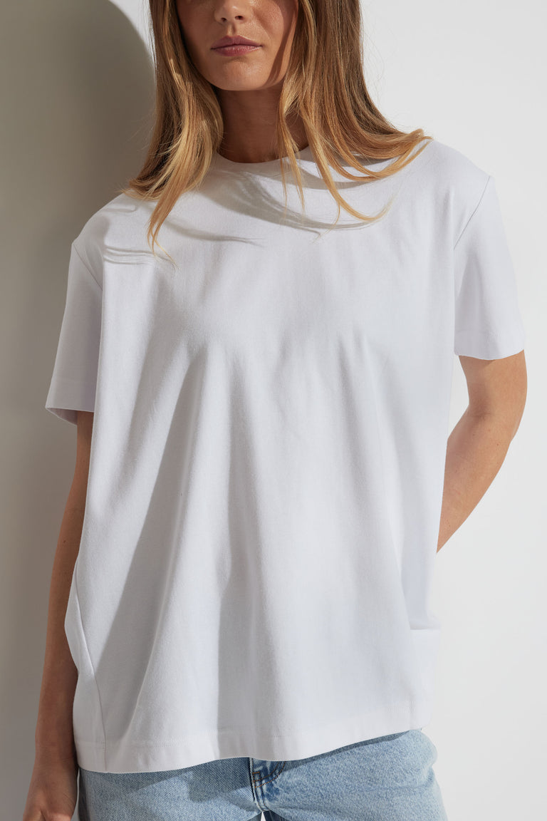 Woman wearing a relaxed white tee with metal detail and light blue denim jeans, styled for effortless everyday wear