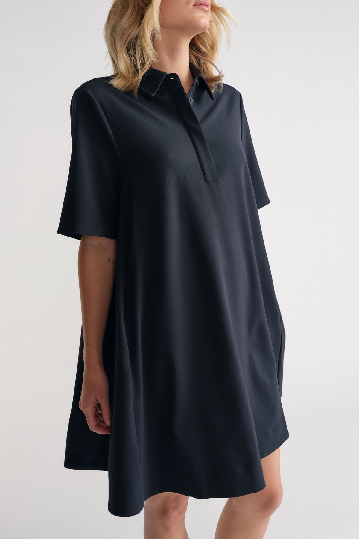 Woman wearing a relaxed-fit navy polo dress with short sleeves and a classic collar for an easy everyday look