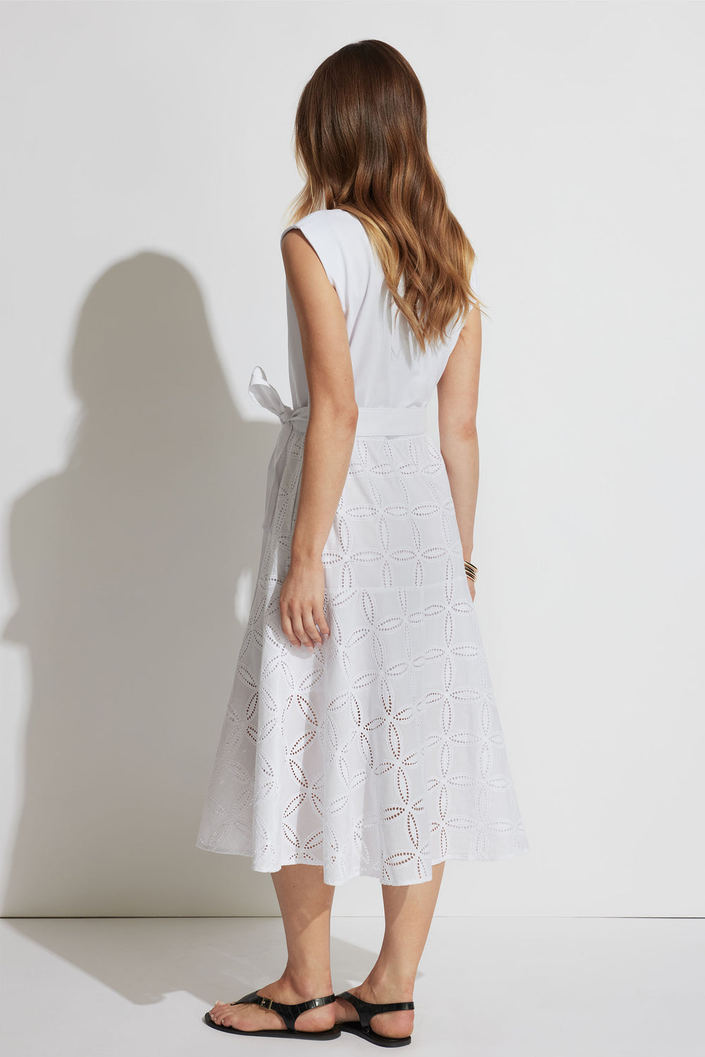 Back view of Eden Broderie Midi Dress with spliced fabric and adjustable waist tie in portrait gallery shot 3