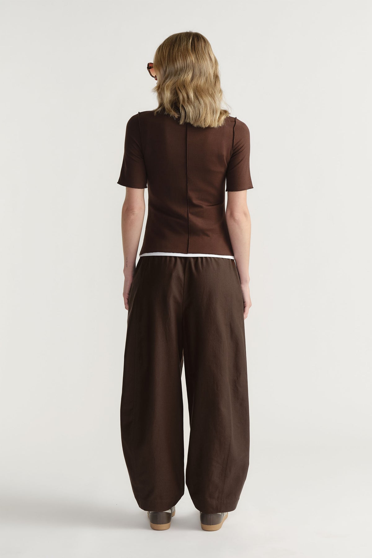 Back view of model wearing fitted brown D-Luxe Short Sleeve Top with mock neck and centre front seam, gallery position 3 portrait