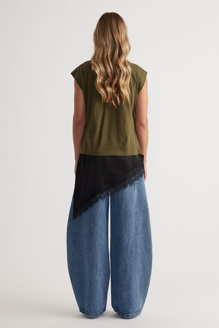 Woman shown from behind wearing an olive green twist detail top paired with wide-leg blue denim jeans and a black lace-trim scarf.