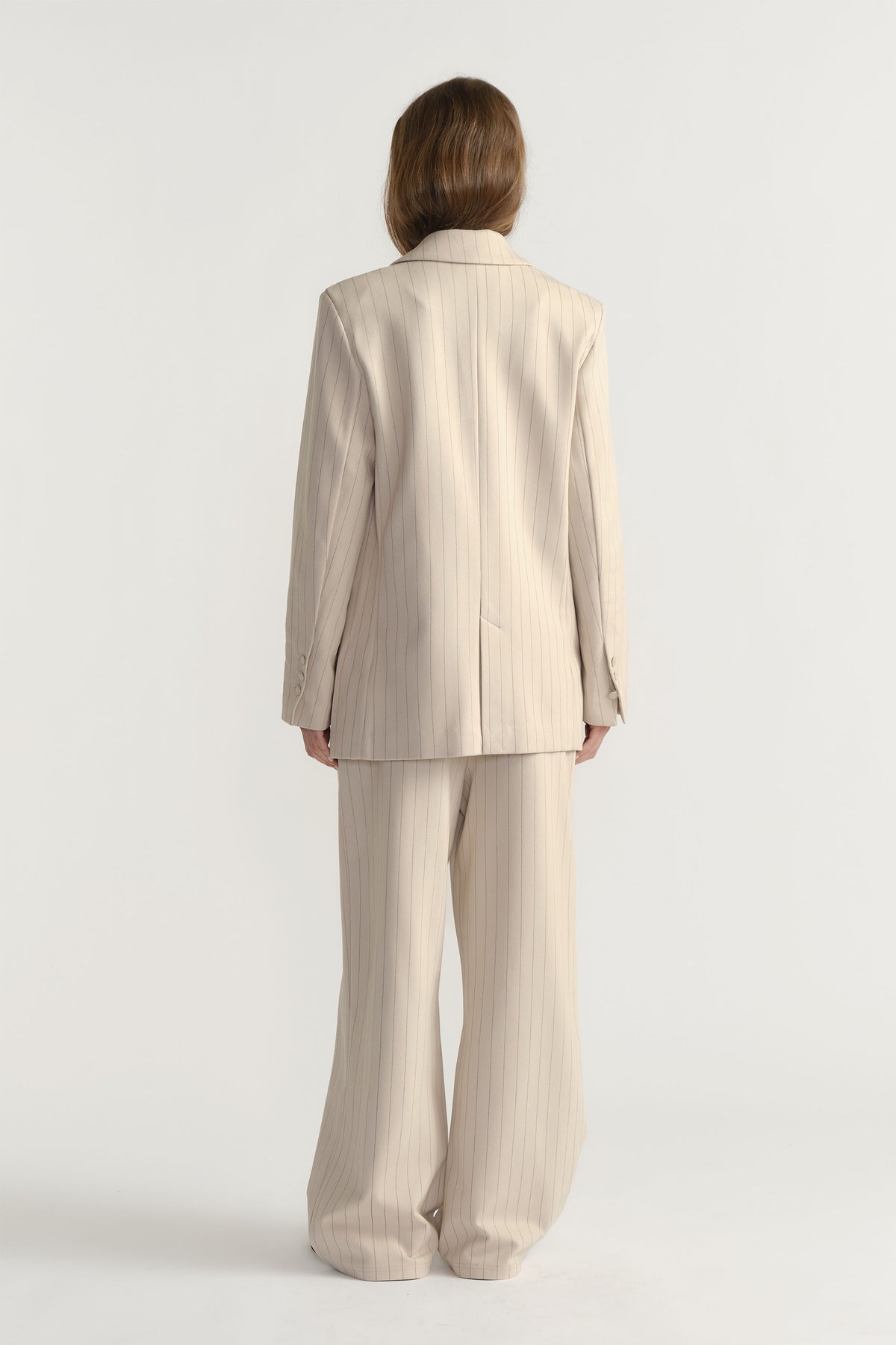 Back view of D-Luxe Pinstripe Blazer in soft beige with subtle stripes, paired with matching wide-leg pants by Decjuba Australian brand