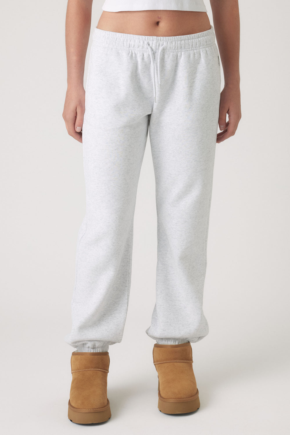 Light grey track pants with elastic cuffs and waistband, paired with tan ankle boots for casual comfort.