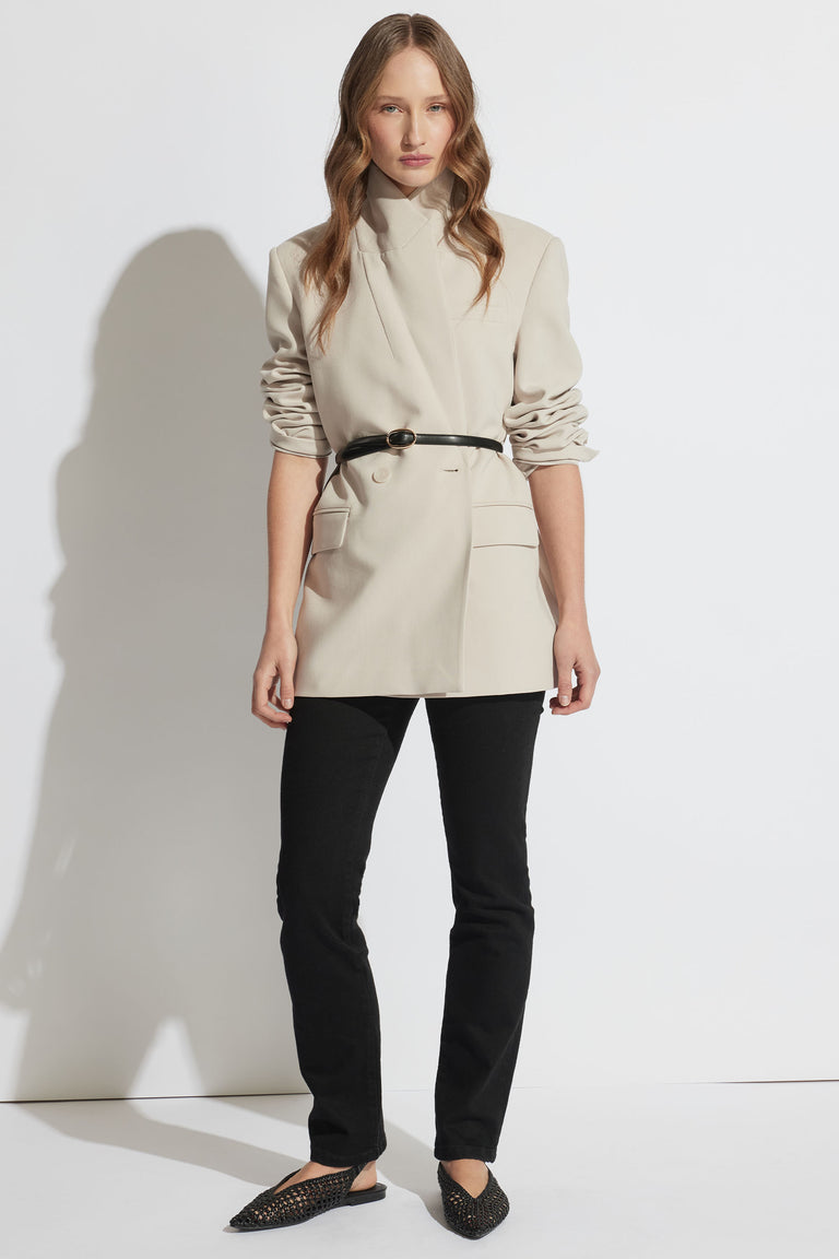 Portrait of a model wearing Billie Straight Leg Jean in black denim paired with a beige blazer and belt, gallery position 1