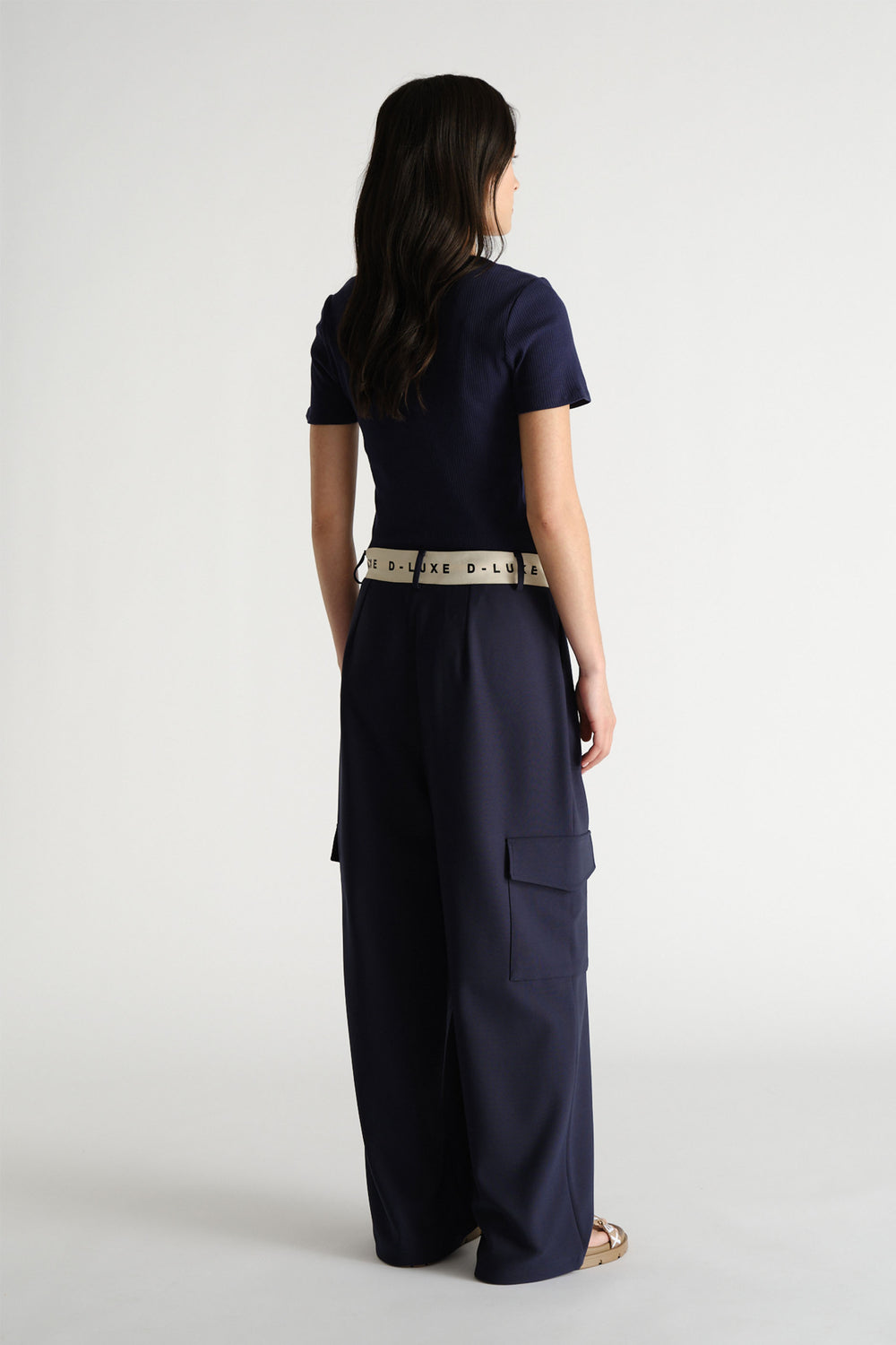 Woman wearing navy wide-leg pants with a branded logo waistband paired with a fitted navy short-sleeve top